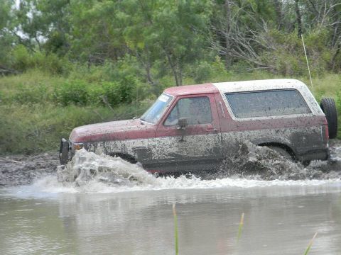 1989 Ford Bronco - This 1989 Ford Bronco navigates a muddy terrain, kicking up water and mud as it goes.