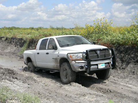 1989 Ford Bronco - This Dodge Ram is navigating a difficult muddy terrain with its front tires deep in the mire.