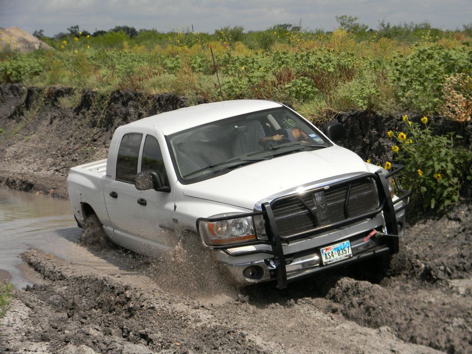 White pickup truck with a bull bar driving through mud and water