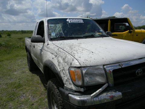 1989 Ford Bronco - This white pickup truck, covered in mud, has a '4 Weekend Wheelers' sticker on its windshield and is parked next to a yellow Jeep.