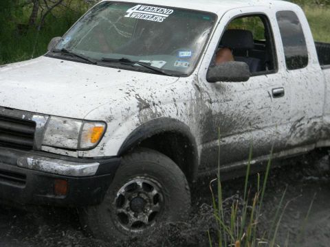 1989 Ford Bronco - Muddy Toyota Tacoma navigates off-road terrain, displaying a "4 WEEKEND WHEELERS" decal.