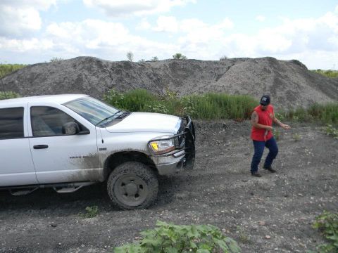 1989 Ford Bronco - A white pickup truck is parked on a dirt road with a man standing nearby and a large pile of dirt in the background.