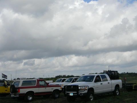 1989 Ford Bronco - Multiple trucks and SUVs are parked outdoors under a cloudy sky.