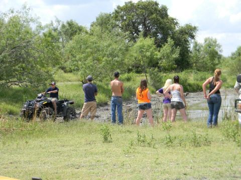 1989 Ford Bronco - People gather to watch an ATV navigate a muddy terrain.