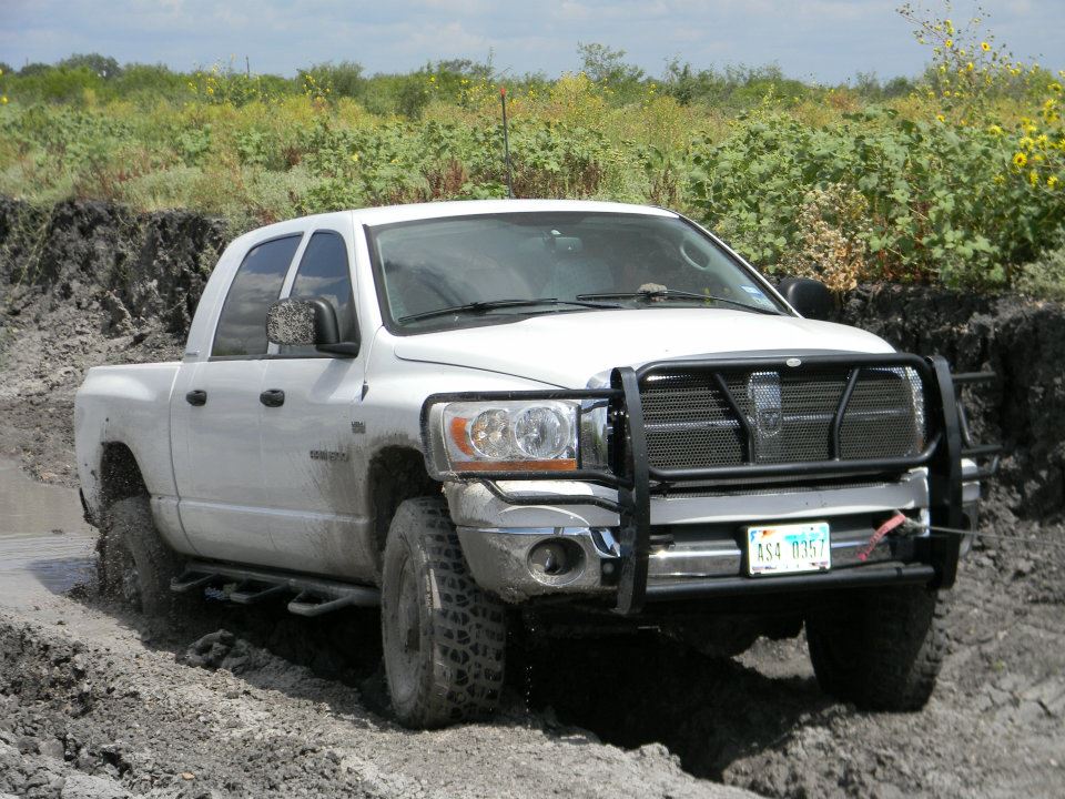 White pickup truck with bull bar driving through mud; license plate ASA 0357
