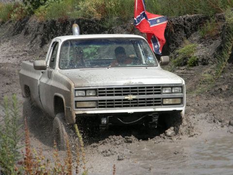 1989 Ford Bronco - This Chevrolet C/K pickup truck is navigating a muddy terrain with a Confederate flag flying.