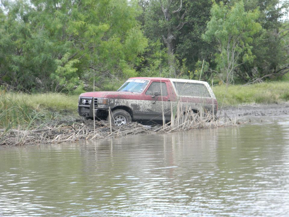 1989 Ford Bronco stuck in mud and water, front bumper partially submerged