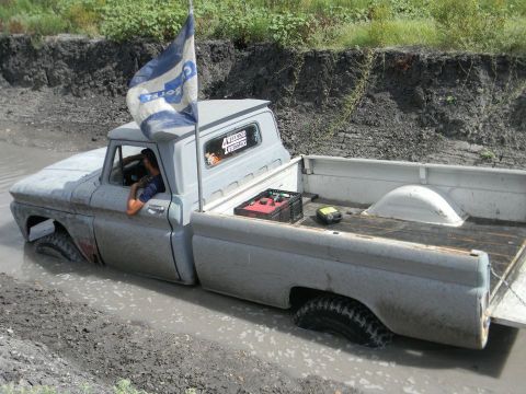 1989 Ford Bronco - Pickup truck is stuck deep in mud, with only the cab and part of the bed visible above the mire.