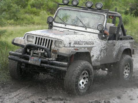 1989 Ford Bronco - Muddy Jeep Wrangler with Harley Davidson graphics navigates a wet, off-road course.