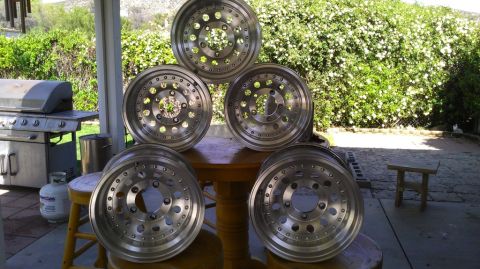 1988 Ford Bronco - A collection of five aluminum wheels are displayed on a table in an outdoor setting with a grill in the background.