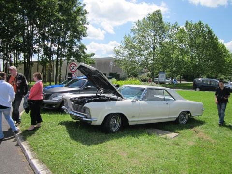 1991 Ford LTD Crown Victoria - A white 1965 Buick Riviera coupe is displayed with its hood open at an outdoor event.
