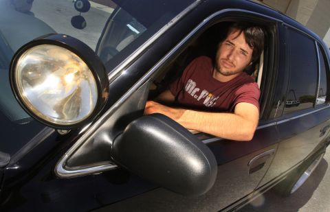 2003 Ford Crown Victoria - man looks out the open window of a black sedan fitted with a pillar-mounted spotlight