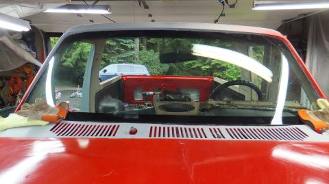 1983 Ford Bronco - The dashboard of a red Ford truck is disassembled, revealing the interior components and steering wheel.