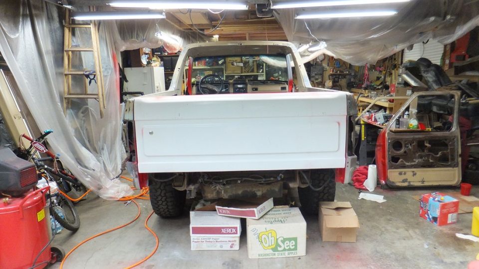 White Ford Bronco in a garage, rear view, undergoing restoration