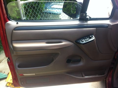 1996 Ford Bronco - Close-up of a vehicle's interior door panel, showing the window controls and a storage compartment.