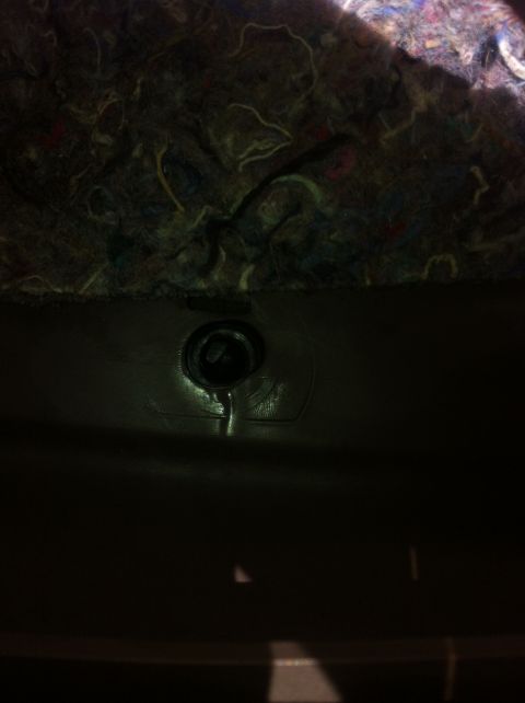 1996 Ford Bronco - A dark interior shot focuses on a single screw fastening a panel, with insulation visible overhead.