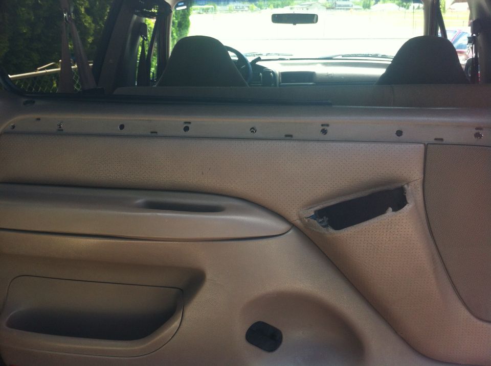interior door panel with torn speaker grille and visible screw holes