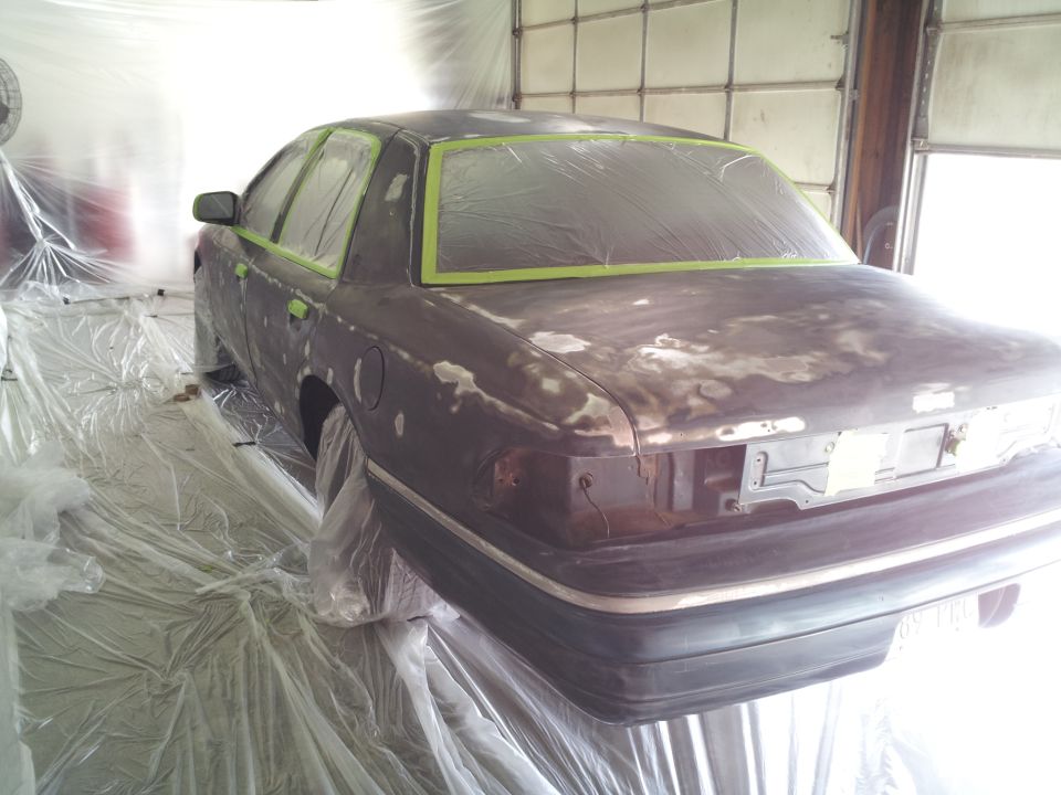 Rear view of a sedan covered in masking tape and primer