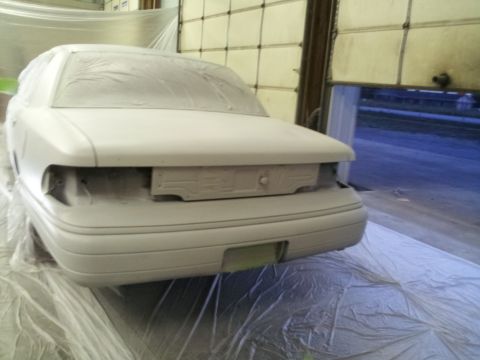 1994 Mercury Grand Marquis - This car is covered in plastic sheeting, likely for painting, in a garage with the door open.