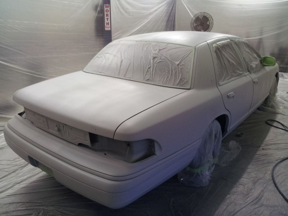 White sedan covered in masking paper, rear view