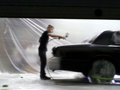 1994 Mercury Grand Marquis - Car being painted in a spray booth with plastic sheeting.