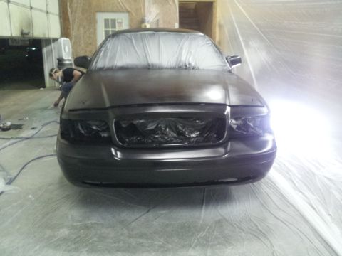 1994 Mercury Grand Marquis - A dark sedan is covered in protective plastic and being prepped for painting in a workshop.