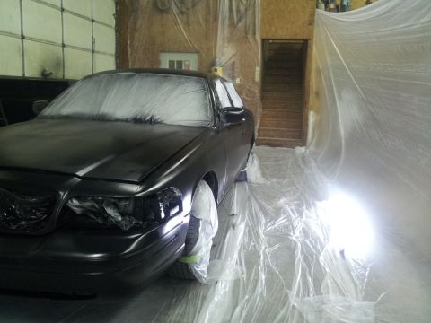 1994 Mercury Grand Marquis - Car covered in plastic sheeting, undergoing preparation for painting in a workshop environment.