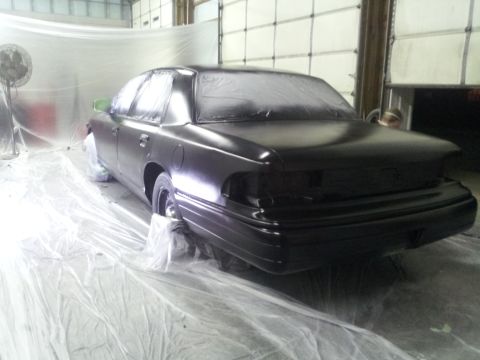 1994 Mercury Grand Marquis - A black sedan is being prepped for painting in a workshop, covered in protective sheeting.