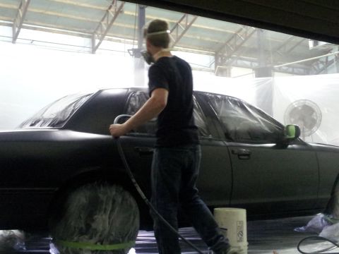 1994 Mercury Grand Marquis - Car undergoing paint work in a spray booth, with protective coverings on the wheels.