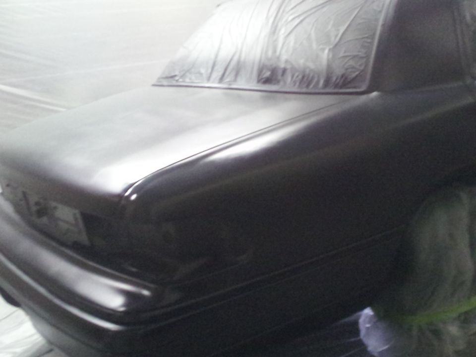 Rear quarter view of black car with rear window covered in plastic