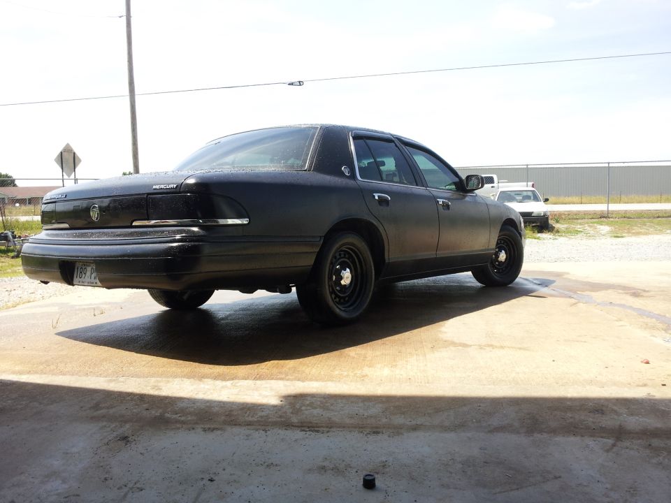 1994 Mercury Grand Marquis, matte black paint, steel wheels, rear 3/4 view
