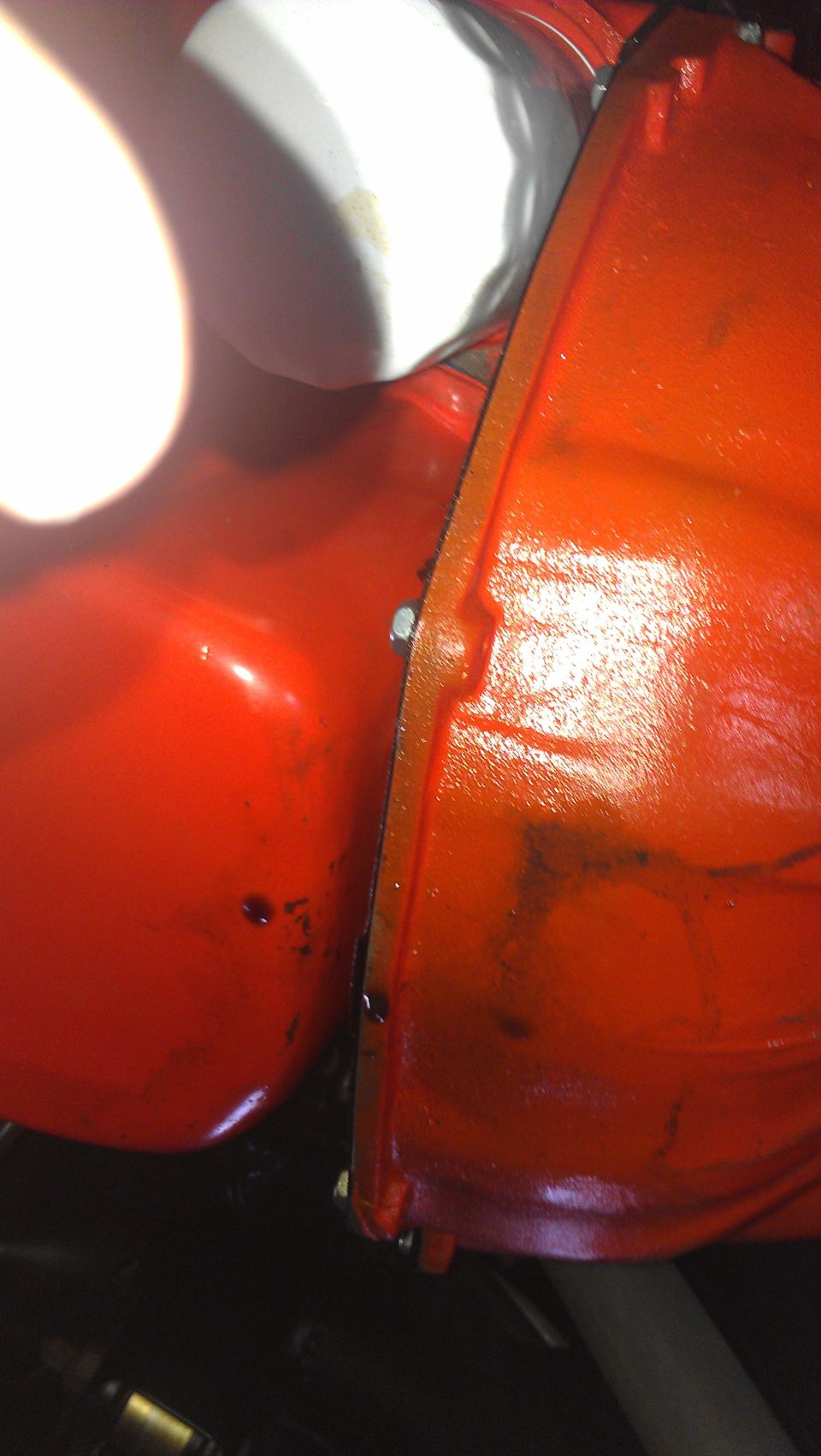 Orange engine block and oil filter with visible bolts and seams