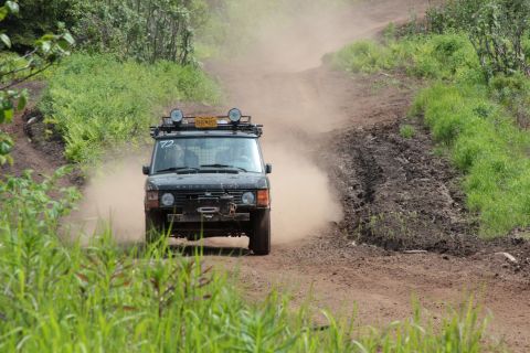 2005 Jeep TJ - A black Range Rover navigates a dusty dirt road, equipped with a roof rack and front winch.