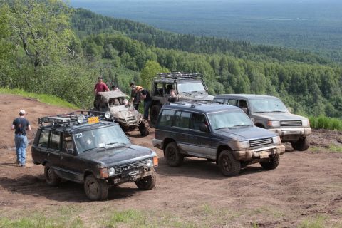 2005 Jeep TJ - Multiple off-road vehicles are gathered on a dirt trail, with a forested landscape behind them.