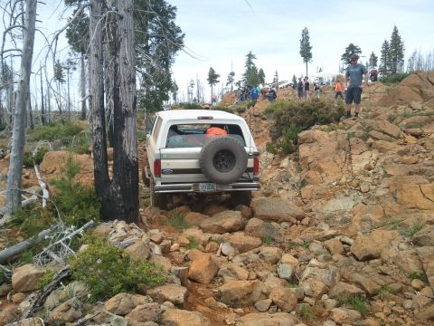 1994 Ford Bronco - A 1994 Ford Bronco navigates a challenging rocky terrain, with spectators gathered on the hillside.