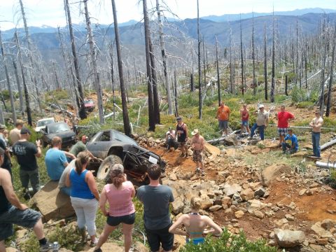 1994 Ford Bronco - A group of off-road vehicles are stuck on a challenging trail in a wooded, mountainous area.