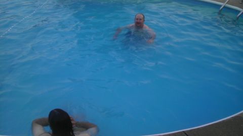2000 Mercury Grand Marquis - People enjoy a swim in a backyard pool on a sunny day.
