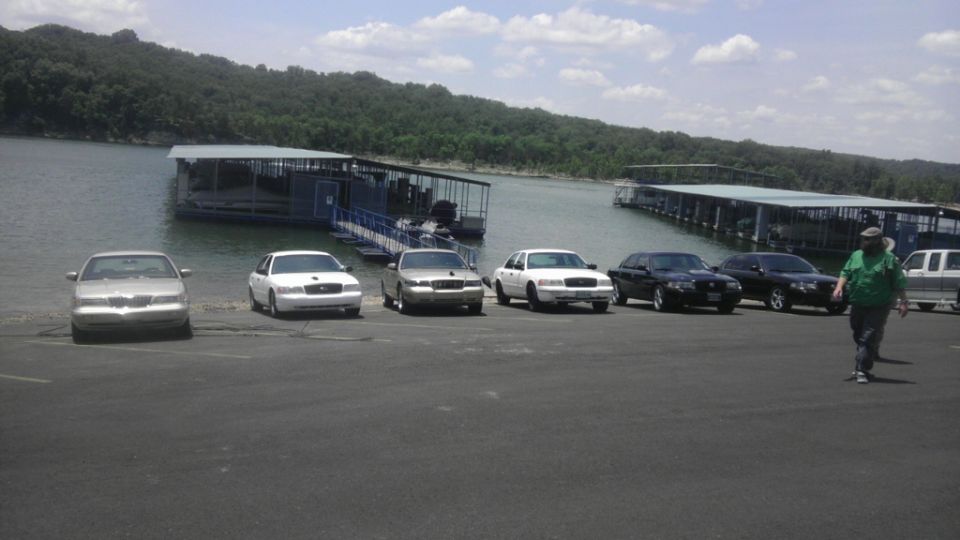 Several sedans parked by a lake with docks in the background