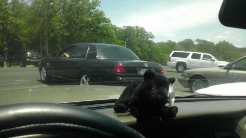 2000 Mercury Grand Marquis - Black 2000 Mercury Grand Marquis seen from inside another vehicle. Other cars are parked nearby.