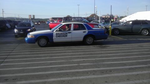 2000 Mercury Grand Marquis - A blue and white police car is parked in a lot, with other vehicles visible in the background.