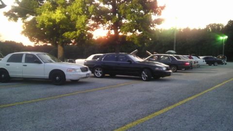 2000 Mercury Grand Marquis - Several sedans, including a white 2000 Mercury Grand Marquis, are parked in an outdoor lot at sunset.