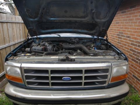 1994 Ford Bronco - Front view of a 1994 Ford Bronco with the hood open, revealing the engine bay and grille.