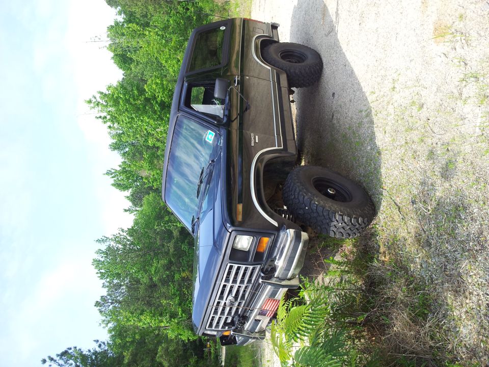 Dark blue SUV with lifted suspension and large tires, parked on a gravel surface