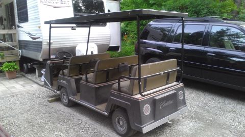 1991 Chevrolet Cheyenne - A golf cart with Cadillac badging is parked outdoors next to a trailer and a black SUV.