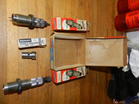 1996 Ford Bronco - Various reloading dies and shell holders are laid out on a wooden surface, suggesting a reloading setup.