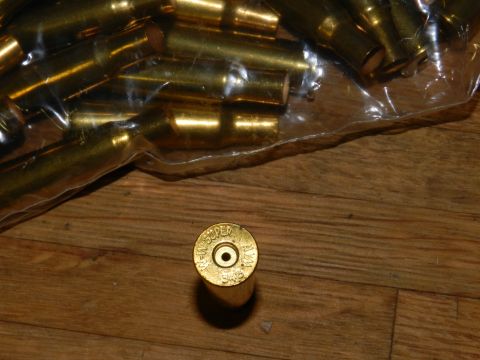 1996 Ford Bronco - A close-up view of brass ammunition casings, some in a plastic bag, on a wooden surface.
