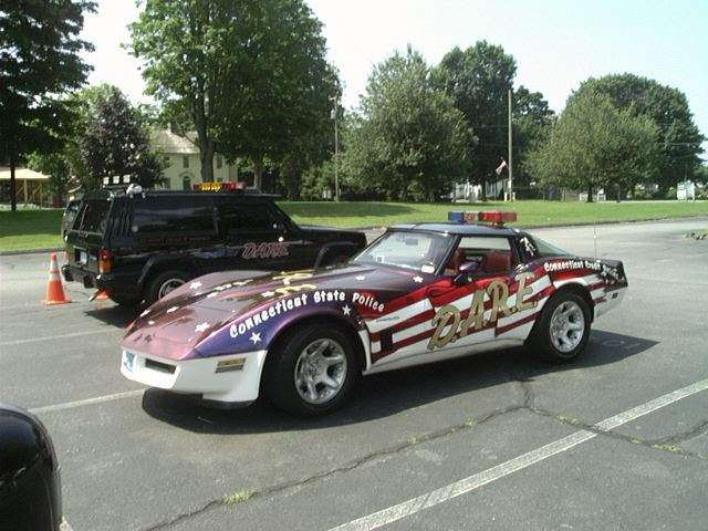 Corvette with DARE livery and Connecticut State Police markings, parked next to a black SUV