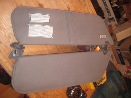 1993 Ford Bronco - pair of gray cloth sun visors with printed warning labels and mounting clips, laid on a wooden surface.