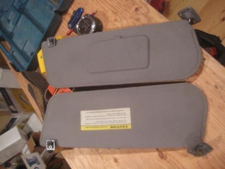 1993 Ford Bronco - Two sun visors are shown, one with a caution label, resting on a wooden table.