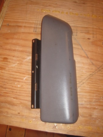 1993 Ford Bronco - A gray plastic automotive part with an attached metal bracket is shown against a wooden background.